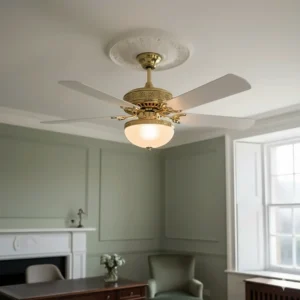 A white Victorian-style ceiling fan with ornate gold accents mounted on a decorative plaster ceiling rose.