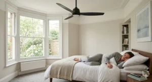 A quiet, modern remote ceiling fan mounted above a bed in a minimalist British bedroom, highlighting its silent operation for a peaceful night's sleep.