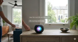 A matte black Apple HomePod mini on an oak sideboard receiving a Siri voice command to turn on the ceiling fan in a brightly lit room.