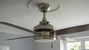 Close-up of the pull-cord mechanism on a brushed-metal ceiling fan with an integrated light.
