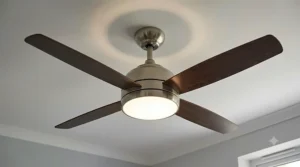 A detailed view of a modern ceiling fan with light, showcasing its sleek brushed-nickel finish.