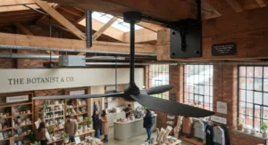 Reversible ceiling fan operating in reverse mode to redistribute trapped warm air downward in a high-ceiling retail outlet.