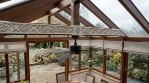 Close-up of a professionally installed ceiling fan mounted securely to the central ridge beam of a white uPVC conservatory.