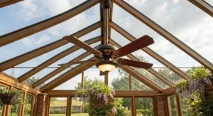 A detailed, photorealistic close-up of a classic brass-accented ceiling fan mounted to the central timber ridge boss of a pitched conservatory glass roof.
