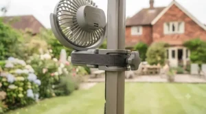 A compact clip-on fan securely attached to a metal gazebo pole for optimal airflow.