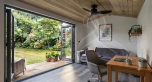 Energy-efficient ceiling fan with an integrated LED light illuminating a cosy garden room at dusk.