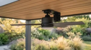 A sleek, contemporary patio ceiling fan with matte black finishes suspended from a modern glass veranda ceiling.