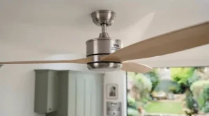 An electrician safely wiring a ceiling fan in a UK property in compliance with local building regulations.